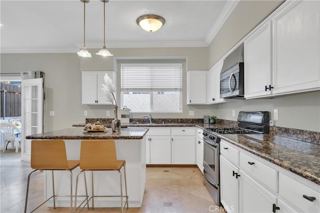 kitchen with white cabinetry, appliances with stainless steel finishes, a center island, and dark stone counters