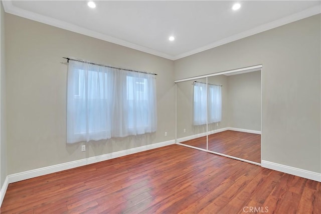 unfurnished bedroom with hardwood / wood-style floors, a closet, and ornamental molding