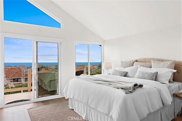 bedroom featuring a water view, high vaulted ceiling, light hardwood / wood-style floors, and access to outside