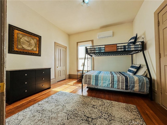 bedroom with a wall mounted air conditioner and dark hardwood / wood-style flooring