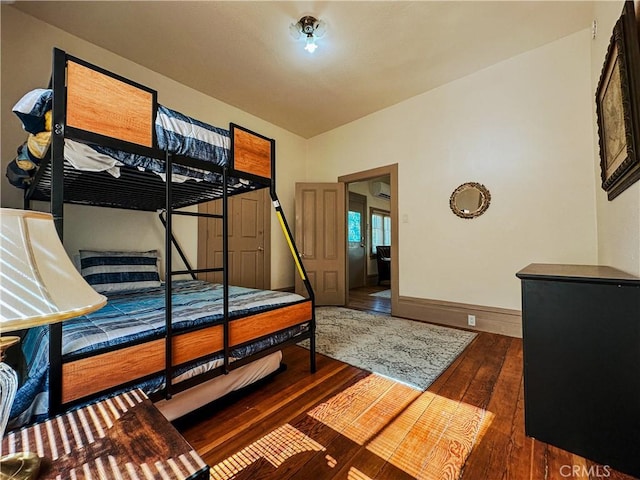 bedroom with dark wood-type flooring and an AC wall unit