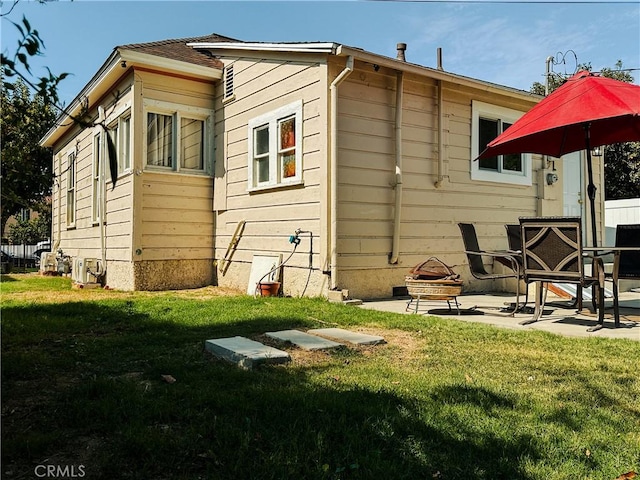 rear view of house featuring a yard, a patio area, and an outdoor fire pit