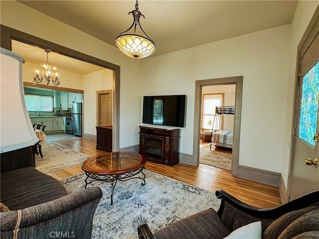 living room featuring sink, an inviting chandelier, and light wood-type flooring