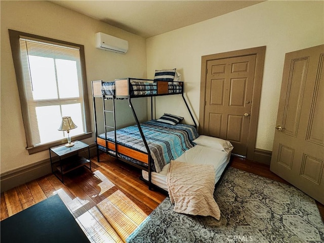 bedroom featuring dark hardwood / wood-style flooring and a wall mounted air conditioner