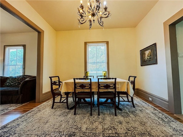 dining area with a notable chandelier and dark hardwood / wood-style flooring