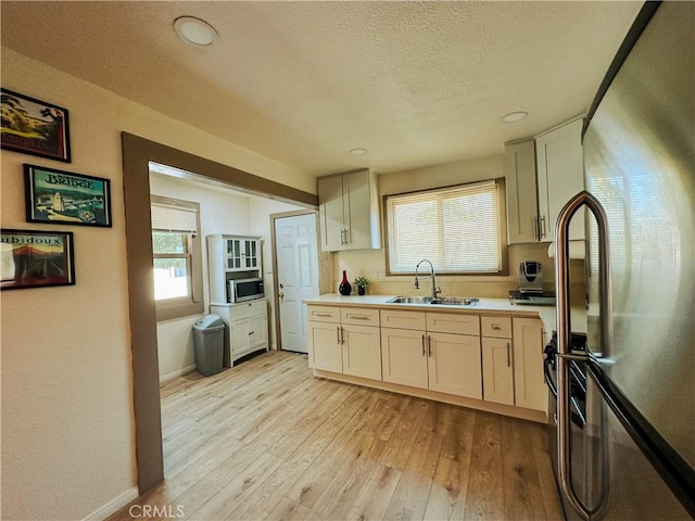 kitchen with stainless steel appliances, light hardwood / wood-style floors, sink, and plenty of natural light