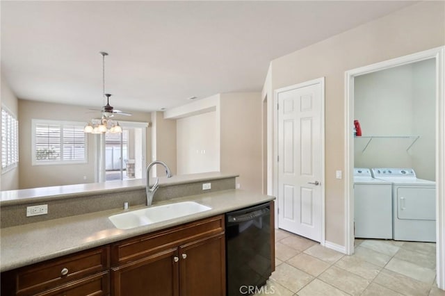 kitchen featuring pendant lighting, sink, light tile patterned floors, washing machine and clothes dryer, and black dishwasher