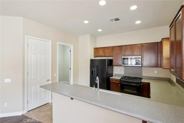 kitchen featuring black appliances, kitchen peninsula, light tile patterned floors, and sink