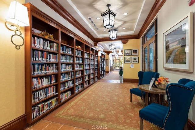 living area with a chandelier, light tile patterned flooring, ornamental molding, built in features, and a tray ceiling