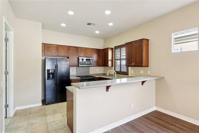 kitchen with sink, black appliances, kitchen peninsula, and a breakfast bar area