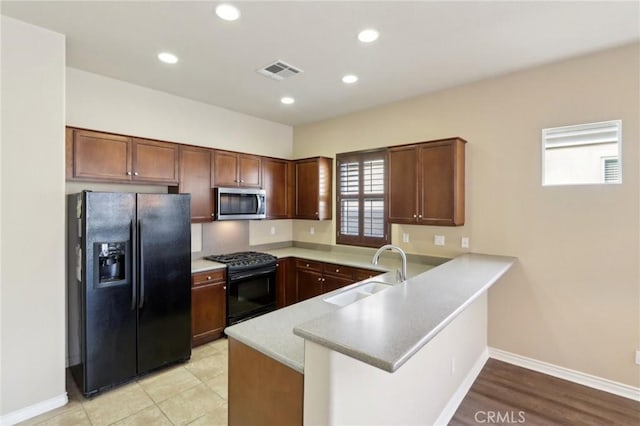 kitchen with sink, black appliances, and kitchen peninsula