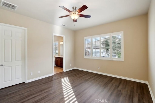 unfurnished bedroom featuring ceiling fan, dark wood-type flooring, and ensuite bath