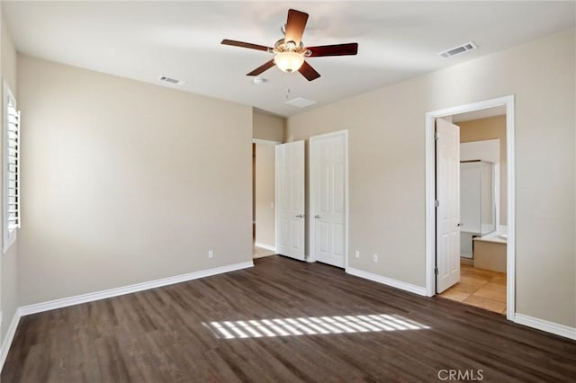 unfurnished bedroom featuring ceiling fan, ensuite bathroom, and dark hardwood / wood-style flooring