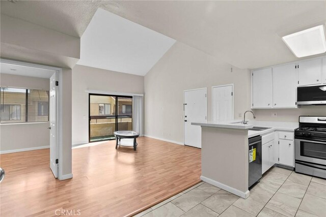 kitchen with sink, appliances with stainless steel finishes, white cabinets, vaulted ceiling, and kitchen peninsula