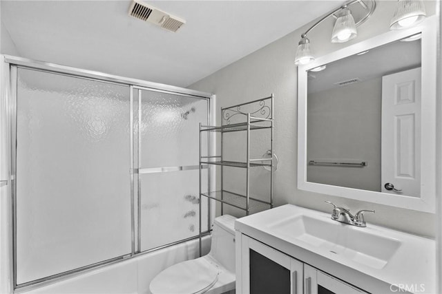 bathroom featuring toilet, shower / bath combination with glass door, visible vents, and vanity