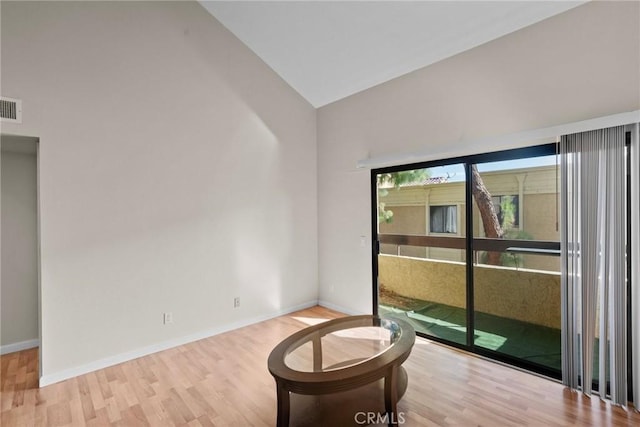 spare room featuring light wood-type flooring, visible vents, lofted ceiling, and baseboards