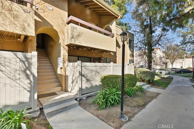 exterior space with fence, a balcony, and stucco siding