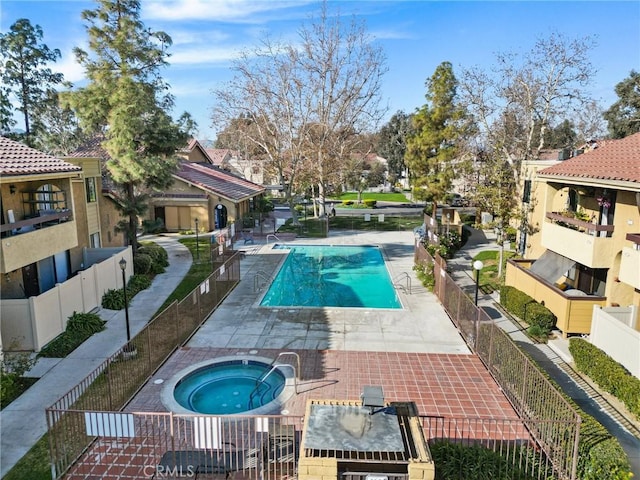 community pool with a patio area, a residential view, fence, and a community hot tub