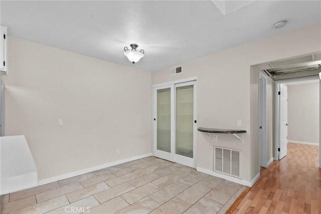 spare room with french doors, visible vents, light wood finished floors, and baseboards