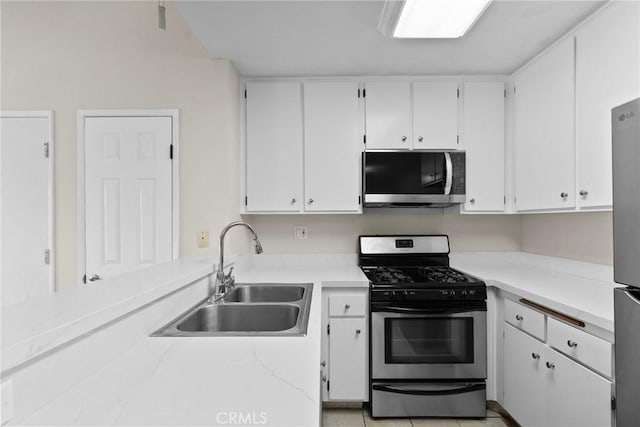 kitchen with appliances with stainless steel finishes, light countertops, a sink, and white cabinetry