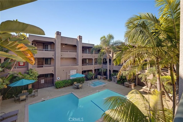 community pool with a patio and a hot tub