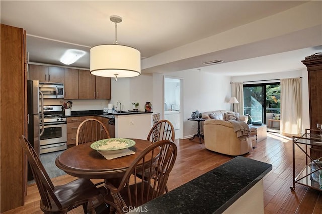 dining space with washer / clothes dryer, wood finished floors, visible vents, and baseboards