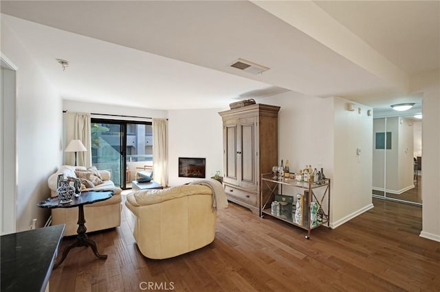 living area with baseboards, a fireplace, visible vents, and wood finished floors