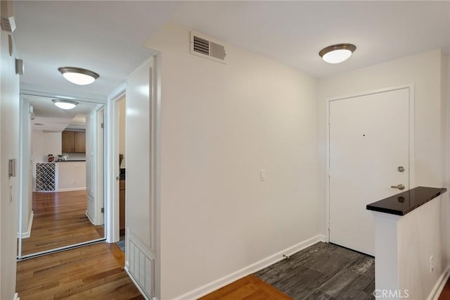 foyer entrance featuring dark wood-style floors, visible vents, and baseboards