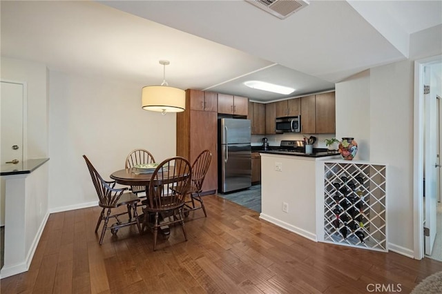 kitchen featuring dark countertops, visible vents, appliances with stainless steel finishes, dark wood-type flooring, and baseboards