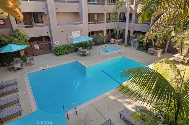 community pool with a community hot tub and a patio area