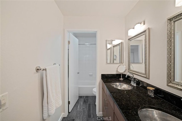 bathroom with double vanity, shower / bath combination, toilet, and a sink