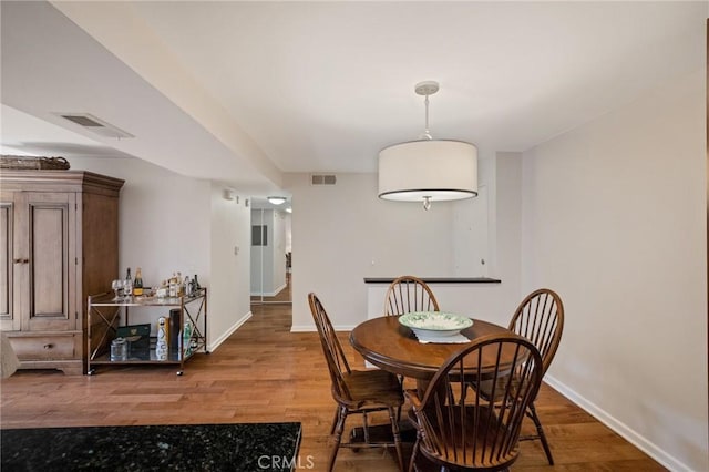 dining area featuring wood finished floors, visible vents, and baseboards