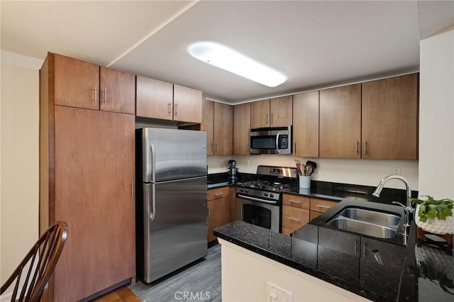 kitchen with stainless steel appliances, a peninsula, a sink, and light wood-style floors