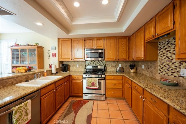 kitchen with light tile patterned flooring, tasteful backsplash, crown molding, appliances with stainless steel finishes, and a raised ceiling