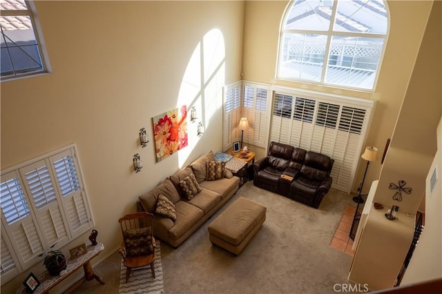 living room featuring a towering ceiling and light colored carpet