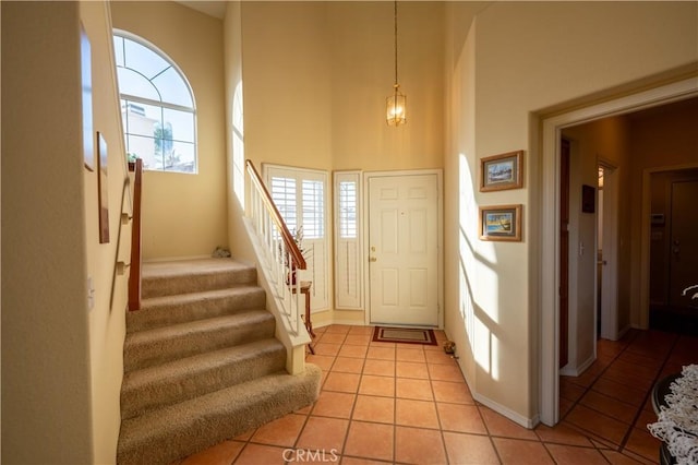 entryway featuring light tile patterned flooring and a towering ceiling