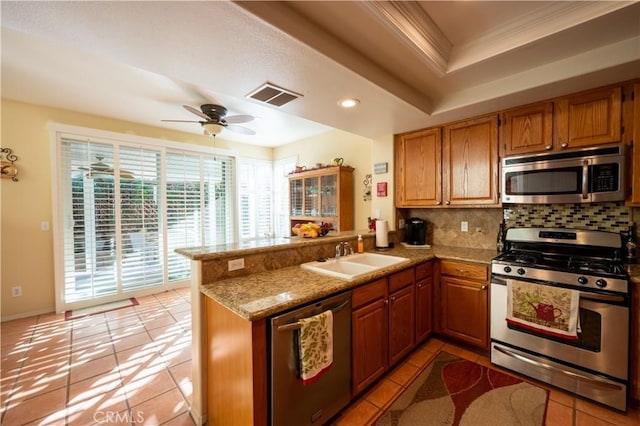 kitchen with stainless steel appliances, a raised ceiling, sink, and kitchen peninsula