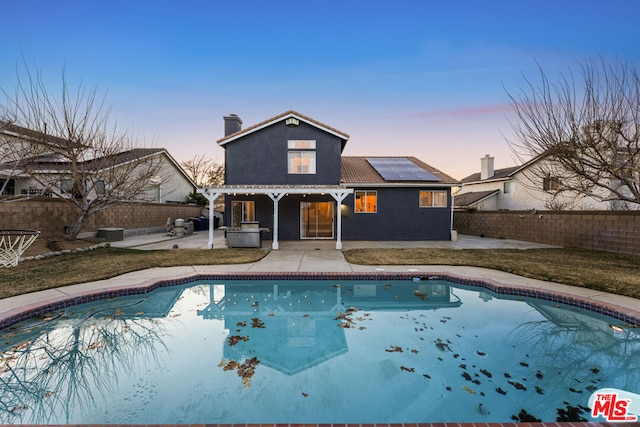 pool at dusk featuring cooling unit and a patio area