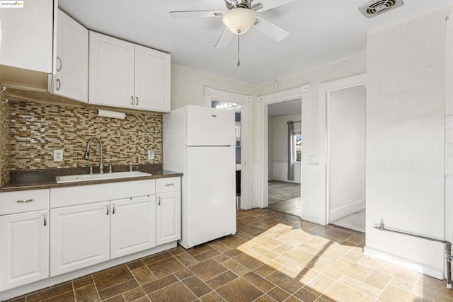 kitchen with white cabinets, white fridge, sink, backsplash, and ceiling fan