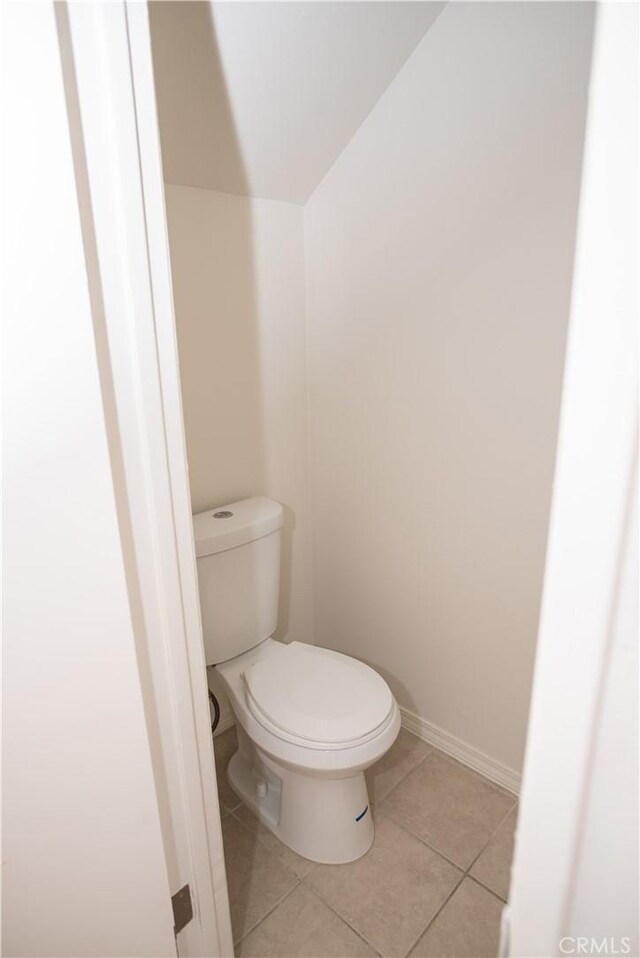 bathroom featuring tile patterned flooring, baseboards, vaulted ceiling, and toilet