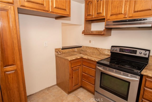 kitchen featuring brown cabinetry, under cabinet range hood, electric range, and light stone counters