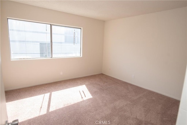 empty room with carpet floors, plenty of natural light, and baseboards