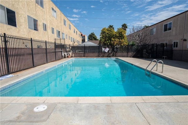 pool with a patio area and fence