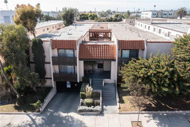 exterior space with driveway, a tiled roof, and stucco siding