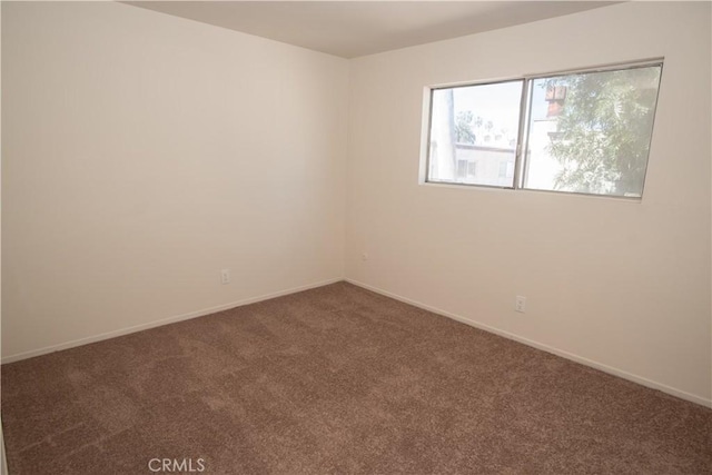 carpeted empty room featuring baseboards