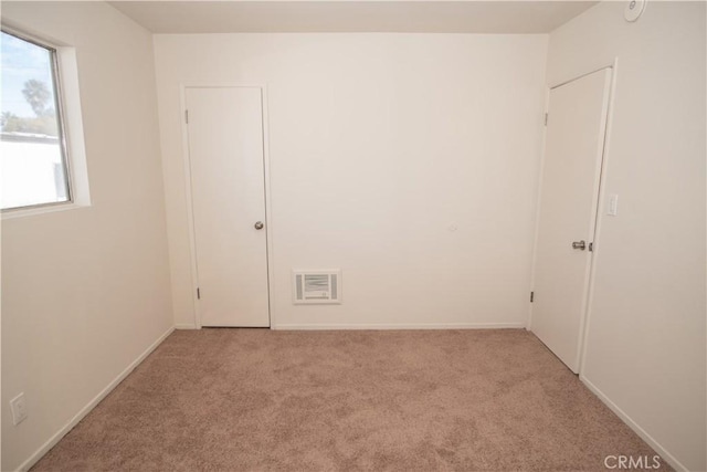 carpeted empty room featuring baseboards and visible vents