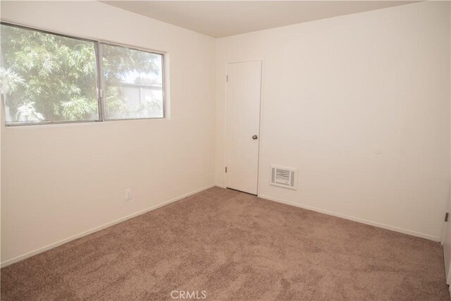 unfurnished room featuring visible vents, light carpet, and baseboards