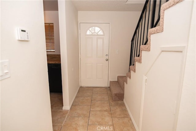 foyer featuring stairway, baseboards, and light tile patterned floors