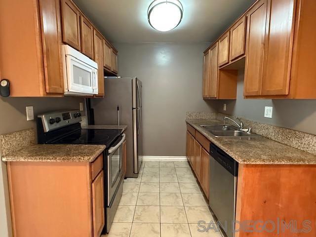 kitchen featuring light tile patterned floors, sink, appliances with stainless steel finishes, and dark stone countertops