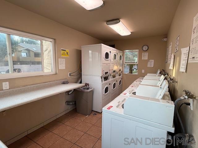 laundry area featuring light tile patterned floors, stacked washer and dryer, and washing machine and clothes dryer